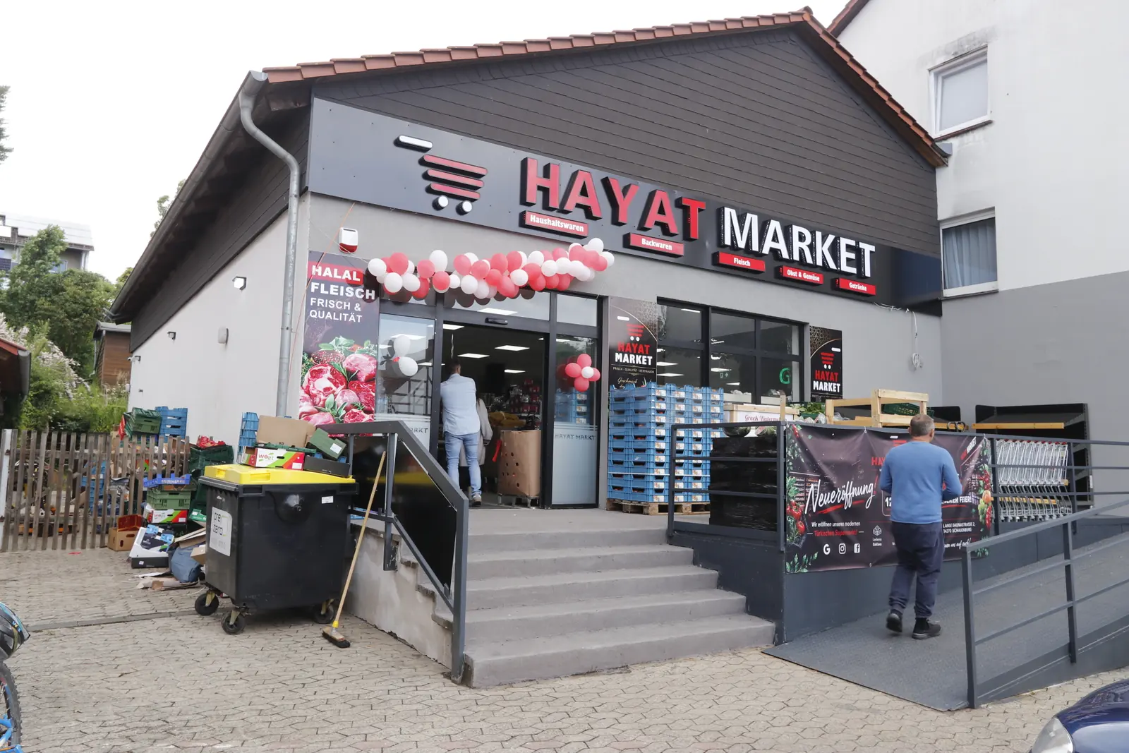 Außenansicht von Hayat Market in Schauenburg mit großem rotem Schriftzug und festlichen Ballons zur Neueröffnung