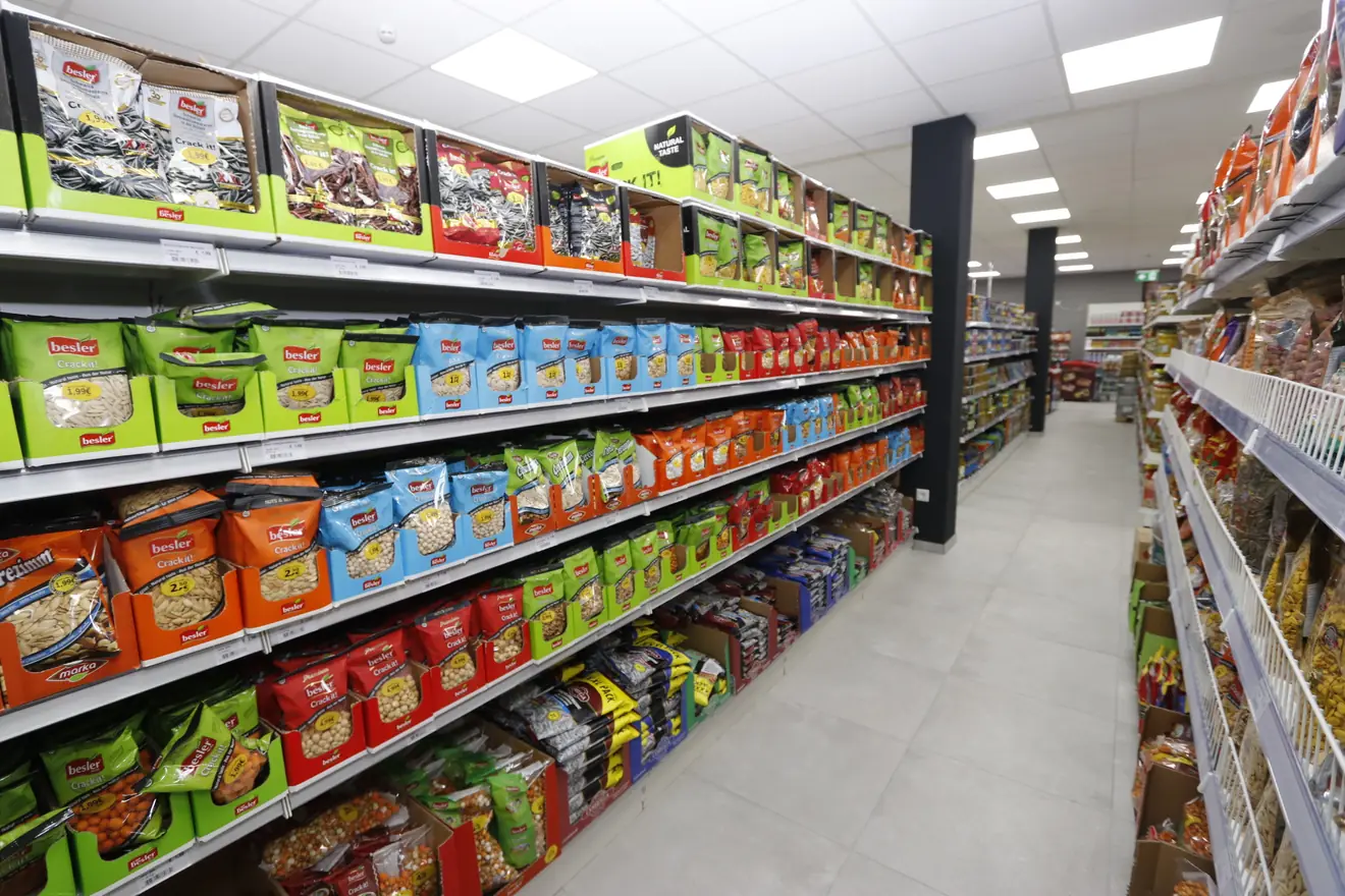 Ordentlich und gerade eingeräumte Regalreihen mit Snacks in einem hellen, breiten Gang bei Hayat Market